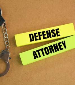 iron handcuffs and colored paper with the word defense attorney.