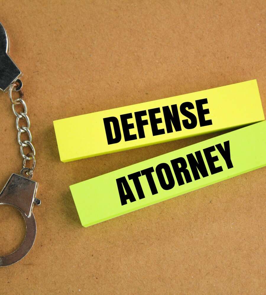 iron handcuffs and colored paper with the word defense attorney.